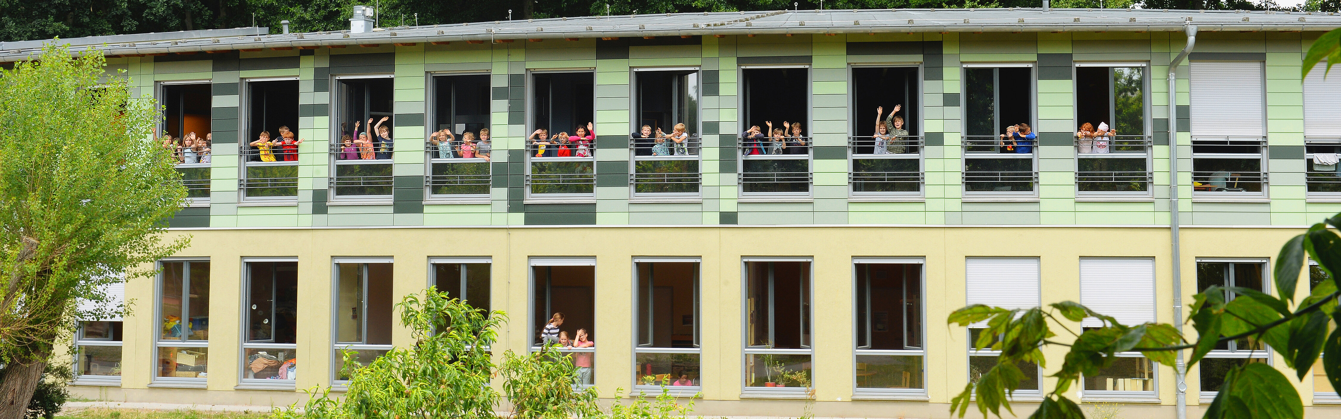 Evangelische Grundschule Kleinmachnow Gebäudeansicht mit winkenden Kindern an den Fenstern