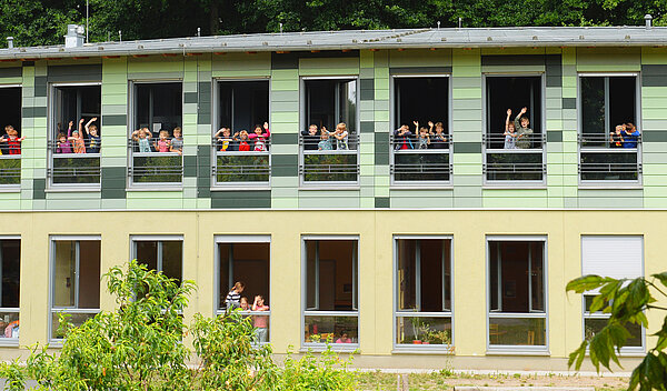 Evangelische Grundschule Kleinmachnow Gebäudeansicht mit winkenden Kindern an den Fenstern